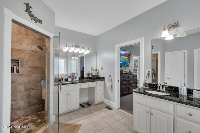 bathroom with tile patterned flooring, a tile shower, and vanity