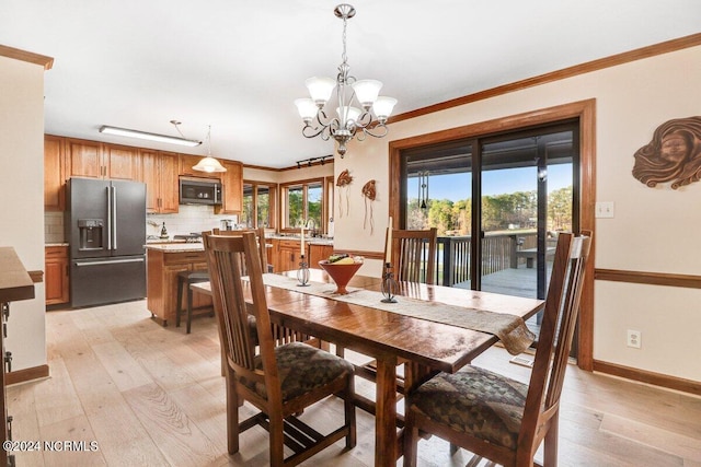 dining area featuring crown molding, sink, a chandelier, and light hardwood / wood-style floors