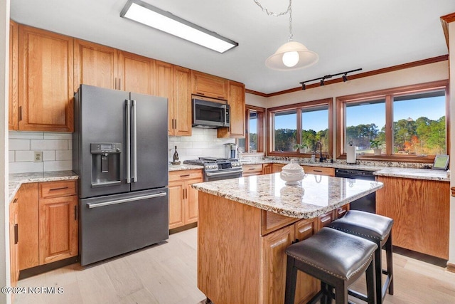 kitchen featuring premium appliances, light stone countertops, light hardwood / wood-style flooring, a kitchen island, and tasteful backsplash