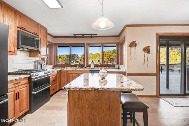 kitchen with double oven range, light hardwood / wood-style floors, hanging light fixtures, and light stone counters