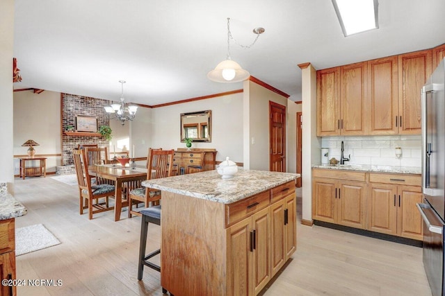 kitchen featuring hanging light fixtures, light hardwood / wood-style floors, a notable chandelier, and light stone countertops