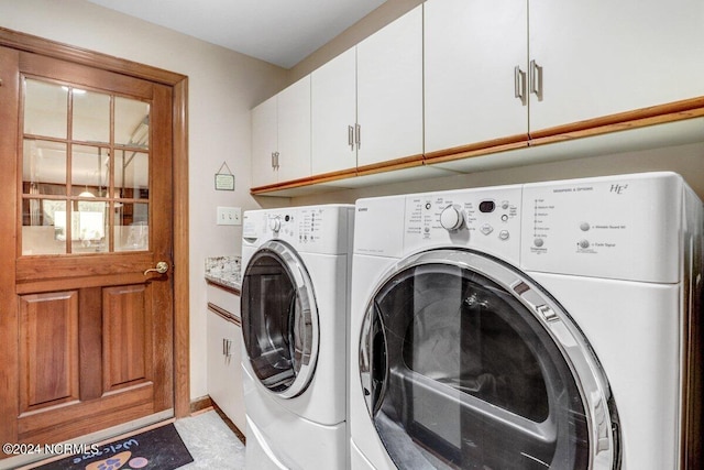 washroom with light tile floors, cabinets, and washing machine and dryer