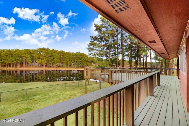 wooden terrace with a water view and a yard