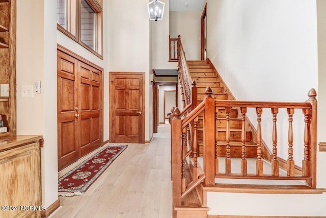 foyer featuring a chandelier, light hardwood / wood-style floors, and a high ceiling