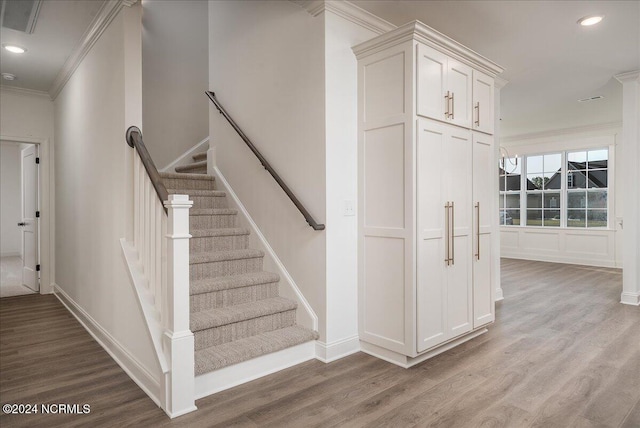 stairs with ornamental molding and wood-type flooring