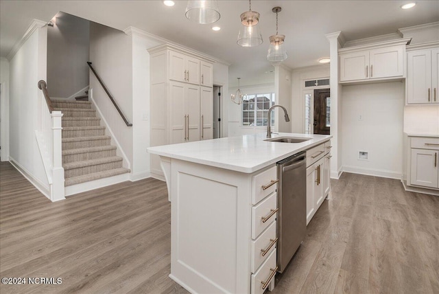 kitchen with an island with sink, sink, crown molding, hanging light fixtures, and white cabinetry