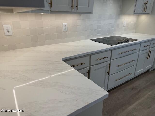 kitchen featuring gray cabinetry, light stone countertops, dark wood-type flooring, and black electric stovetop