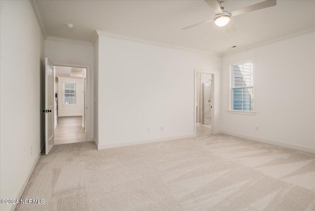 spare room with ceiling fan, light colored carpet, crown molding, and a wealth of natural light