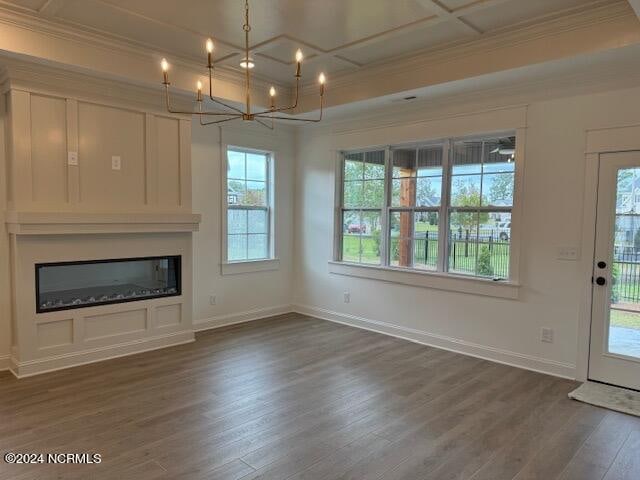 unfurnished living room with a notable chandelier, crown molding, coffered ceiling, and dark wood-type flooring