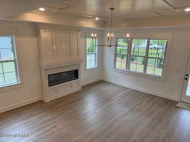 unfurnished living room with hardwood / wood-style flooring, crown molding, and a chandelier