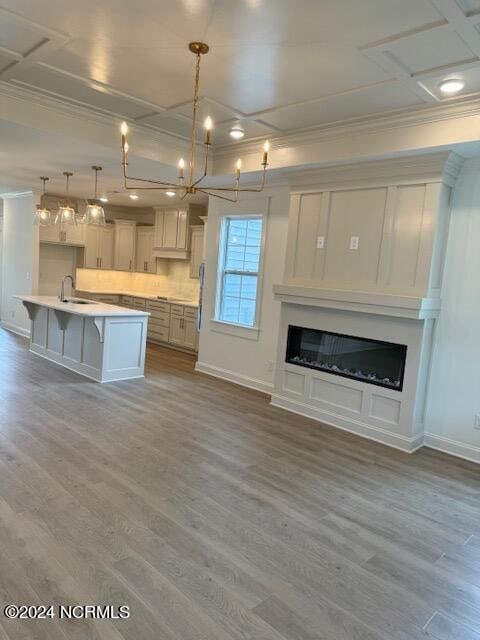 kitchen with pendant lighting, a center island with sink, light hardwood / wood-style flooring, a kitchen breakfast bar, and crown molding