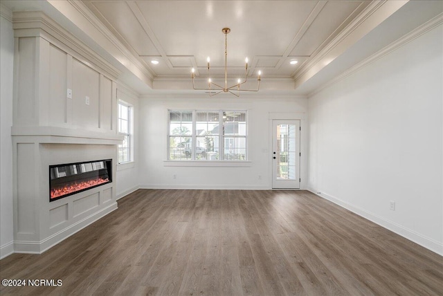 unfurnished living room featuring wood-type flooring, a chandelier, and ornamental molding