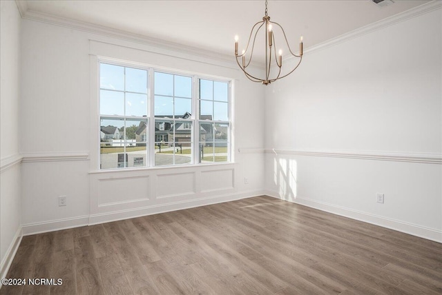 unfurnished room featuring an inviting chandelier, crown molding, and hardwood / wood-style floors