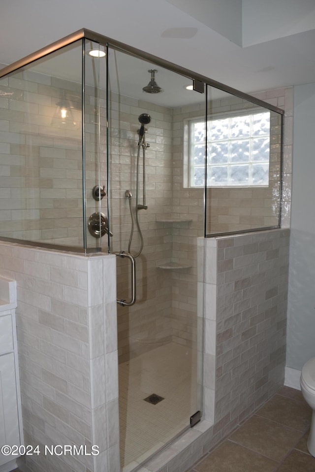 bathroom with vanity, a shower with door, tile patterned flooring, and toilet