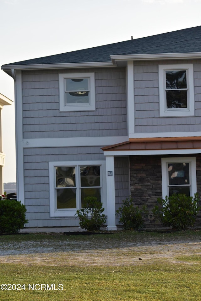 view of front of property with a shingled roof and stone siding