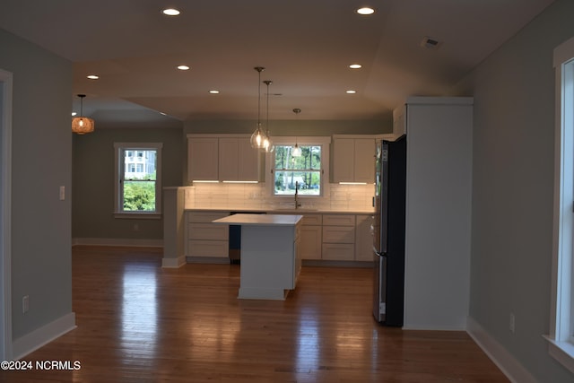 kitchen with hardwood / wood-style floors, sink, black fridge, a center island, and backsplash