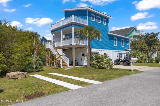 beach home with a front lawn, a balcony, and covered porch