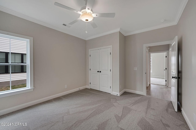 unfurnished bedroom featuring ceiling fan, light colored carpet, ornamental molding, and a closet