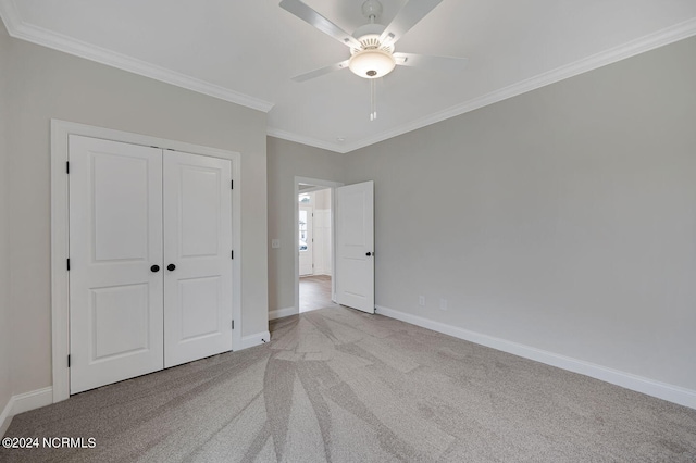 unfurnished bedroom featuring light carpet, a closet, ceiling fan, and crown molding