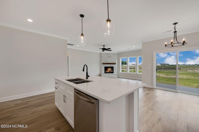 kitchen with an island with sink, stainless steel dishwasher, hanging light fixtures, and sink