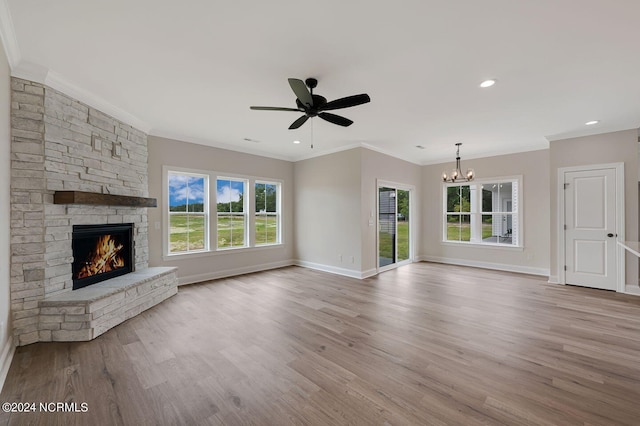 unfurnished living room featuring a fireplace, a healthy amount of sunlight, ceiling fan with notable chandelier, and ornamental molding