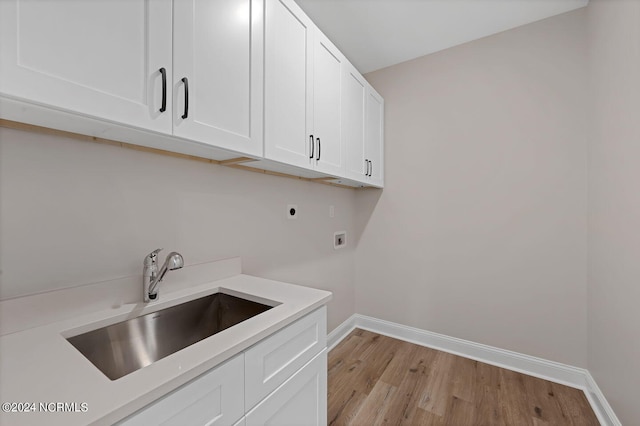 clothes washing area featuring hookup for an electric dryer, washer hookup, light wood-type flooring, cabinets, and sink