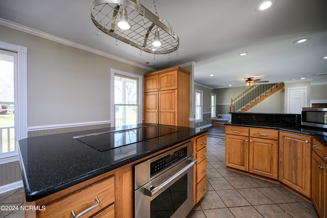 kitchen featuring ceiling fan, stainless steel appliances, a center island, and plenty of natural light