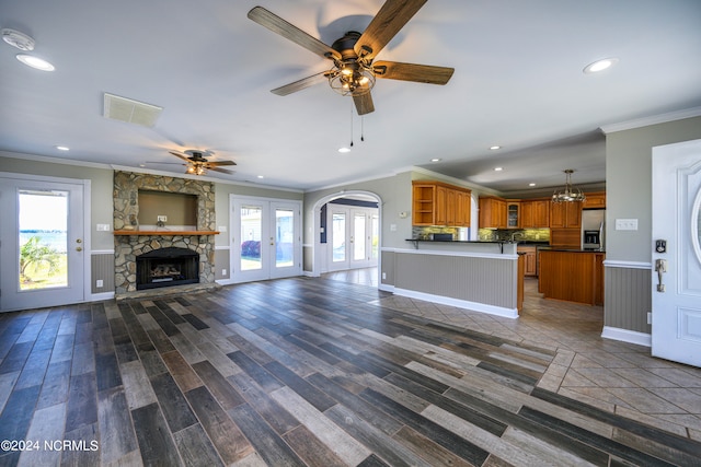 unfurnished living room featuring ceiling fan, a stone fireplace, plenty of natural light, and hardwood / wood-style floors