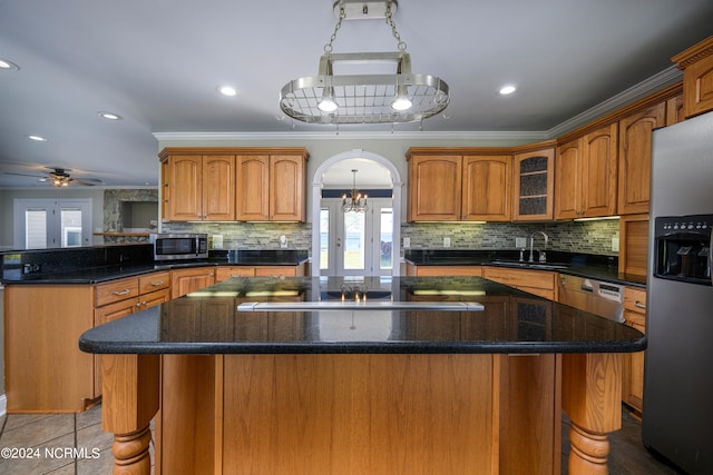 kitchen featuring backsplash, a kitchen island, ceiling fan with notable chandelier, and stainless steel appliances