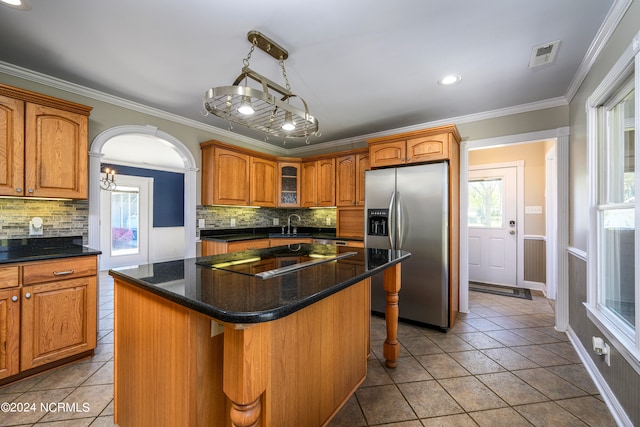 kitchen with light tile floors, stainless steel fridge with ice dispenser, a kitchen island, a breakfast bar area, and tasteful backsplash