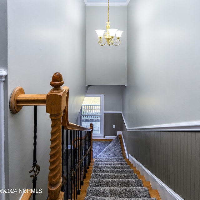 staircase featuring crown molding, a notable chandelier, and dark wood-type flooring