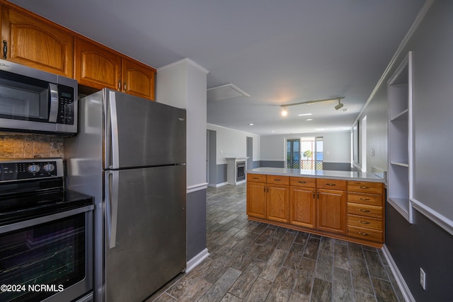 kitchen featuring dark hardwood / wood-style floors, kitchen peninsula, crown molding, appliances with stainless steel finishes, and track lighting