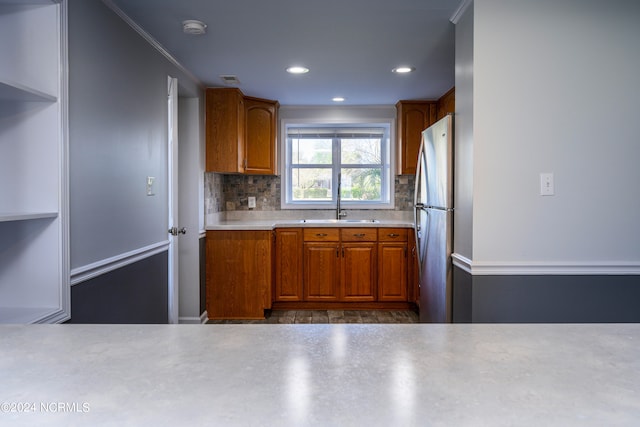 kitchen with stainless steel fridge, crown molding, sink, and tasteful backsplash