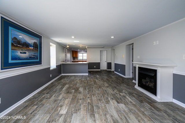 unfurnished living room featuring crown molding and dark wood-type flooring