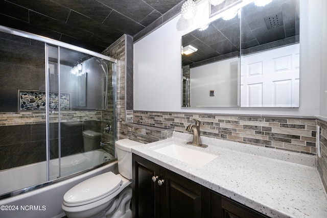 full bathroom featuring tile walls, toilet, enclosed tub / shower combo, tasteful backsplash, and vanity