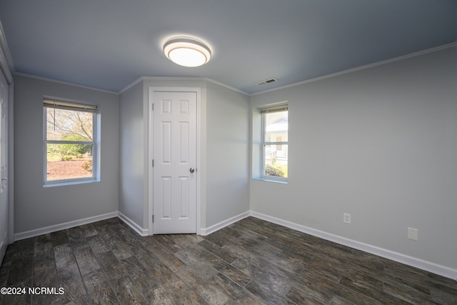 spare room with ornamental molding and dark wood-type flooring