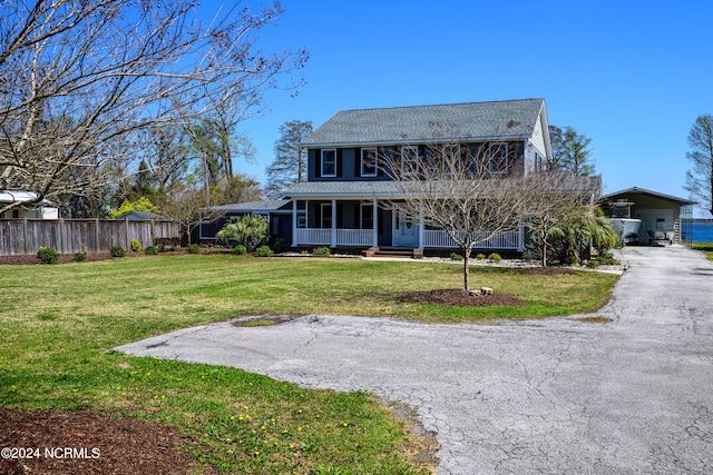 rear view of property with covered porch and a lawn