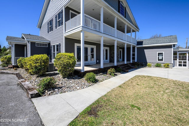 view of front of home with a balcony, covered porch, and a front lawn