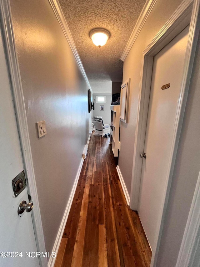 hallway with crown molding, dark wood-type flooring, and a textured ceiling