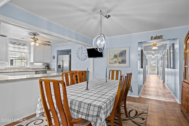 dining room with ornamental molding, light hardwood / wood-style flooring, sink, and ceiling fan with notable chandelier