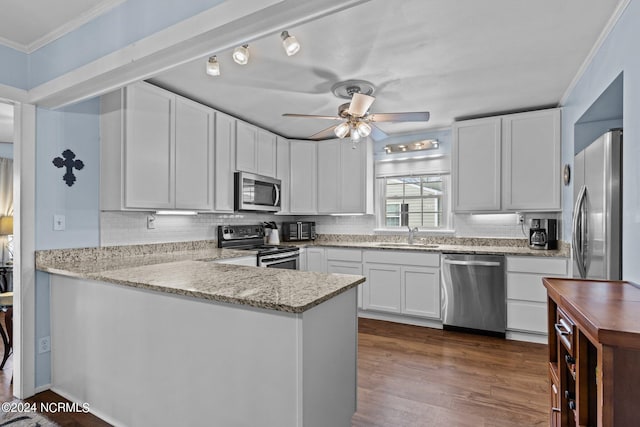 kitchen with ceiling fan, rail lighting, ornamental molding, appliances with stainless steel finishes, and white cabinets