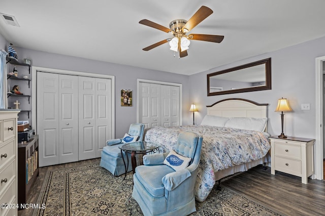 bedroom featuring dark hardwood / wood-style flooring, ceiling fan, and multiple closets