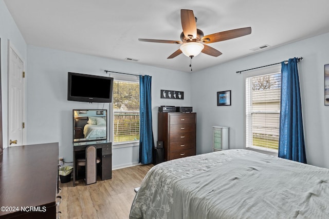 bedroom featuring ceiling fan, light hardwood / wood-style floors, and multiple windows