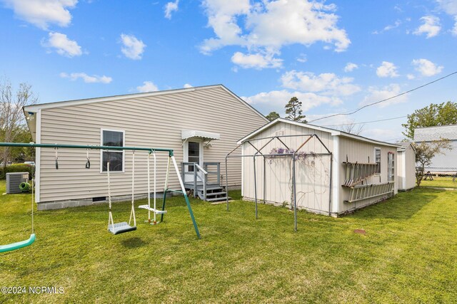 back of house with central air condition unit, a storage shed, and a lawn