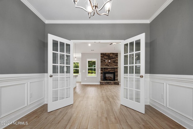 interior space featuring a notable chandelier, a fireplace, ornamental molding, and light hardwood / wood-style floors