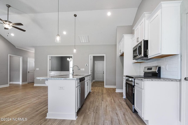 kitchen featuring appliances with stainless steel finishes, a kitchen island with sink, white cabinetry, light stone countertops, and decorative light fixtures