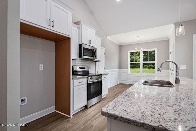 kitchen featuring stainless steel appliances, decorative light fixtures, sink, and white cabinets