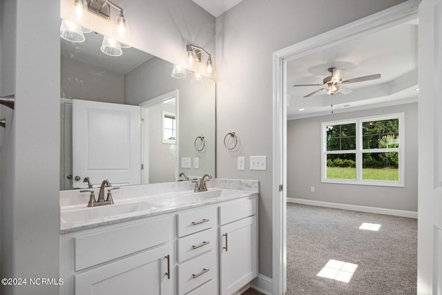 bathroom with ceiling fan, vanity, a raised ceiling, and a wealth of natural light