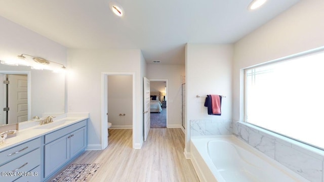 bathroom featuring vanity, hardwood / wood-style flooring, a tub, and toilet