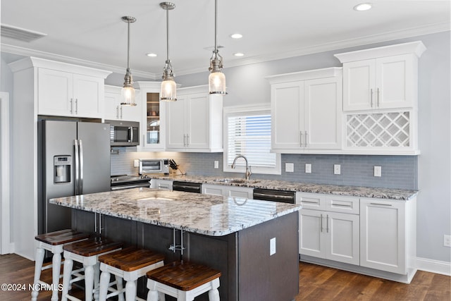 kitchen featuring a kitchen island, tasteful backsplash, stainless steel appliances, and decorative light fixtures